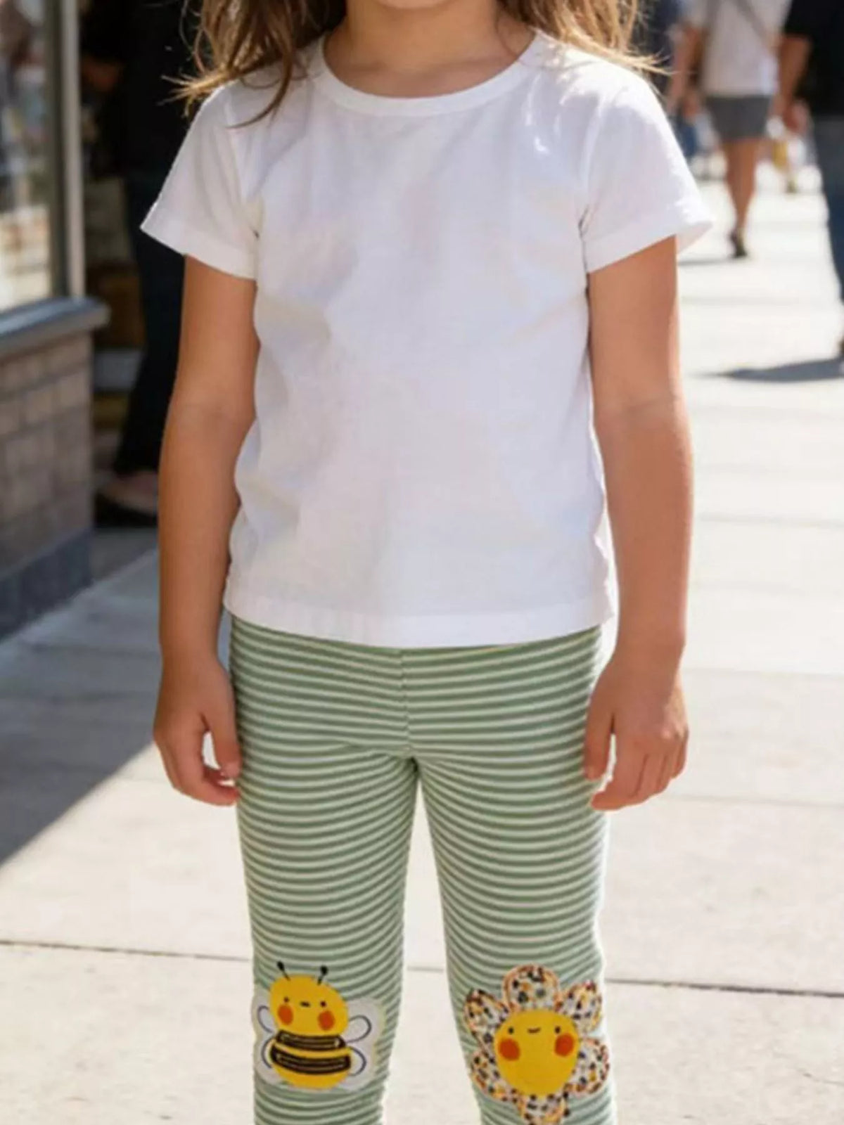 Green striped bee-and-flower applique leggings on a child