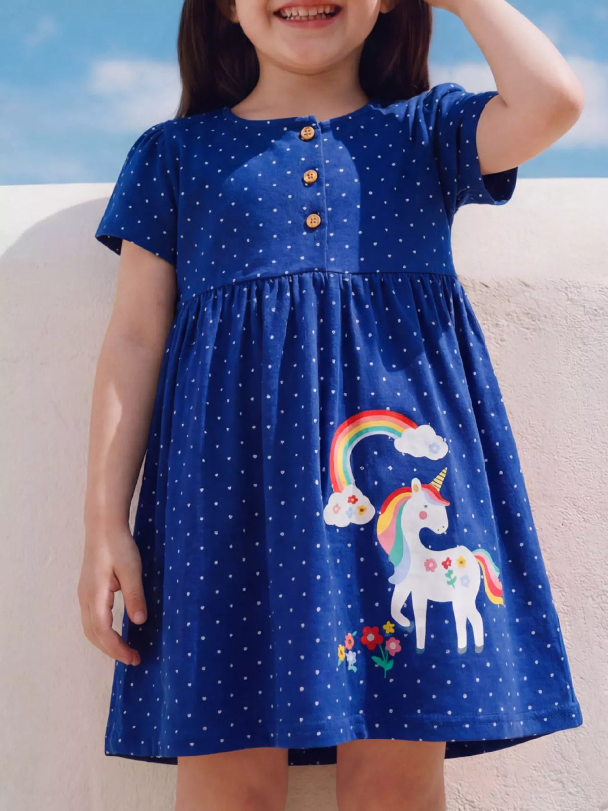 Blue polka-dot dress with unicorn and rainbow motifs on a child