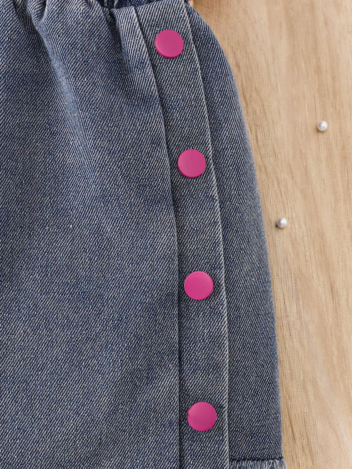 Pink buttons down the gray denim skirt
